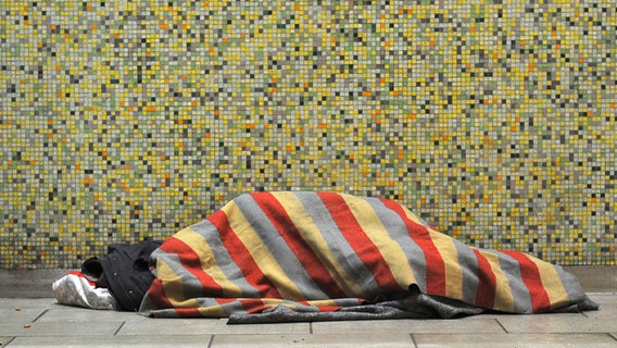 In einer U-Bahn-Station in Hannover liegt ein Obdachloser unter einer Decke. © dpa/picture alliance Foto: Barbora Prekopova