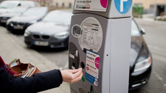 Eine Hand wirft Geld in einen Parkautomaten. © dpa | picture alliance Foto: Julian Stratenschulte