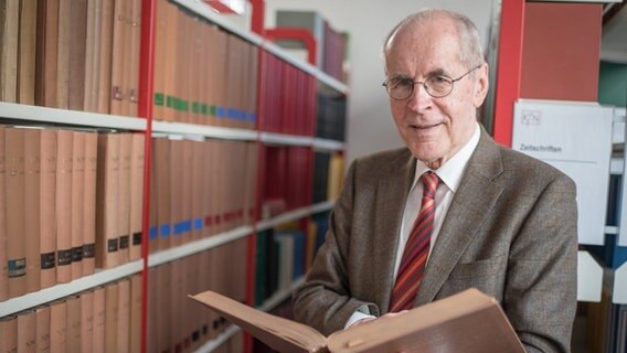 Der Kriminologe Christian Pfeiffer steht mit einem Buch vor einem Regal. © picture alliance/dpa/Ole Spata Foto: Ole Spata