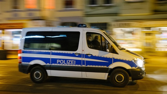 Ein Mannschaftswagen der Polizei fährt bei Nacht auf der sonst belebten Limmerstraße. © picture alliance/dpa Foto: Ole Spata