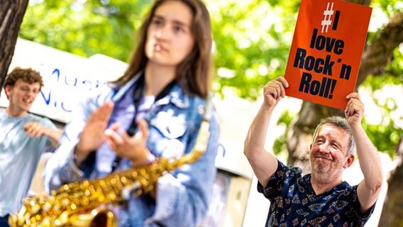 Menschen demonstrieren vor dem niedersächsischem Landtag gegen die aus ihrer Sicht prekäre Situation der Popularkultur - der Schriftzug "I love Rock'n Roll" ist dabei auf einem Plakat zu lesen. © Moritz Frankenberg/dpa Foto: Moritz Frankenberg