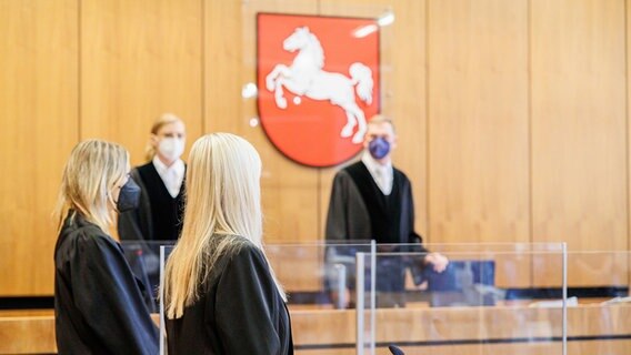 Die Angeklagte (3.v.l) und ihre Pflichtverteidigerin Anne Deneke (l) stehen vor Prozessbeginn in einem Gerichtssaal im Landgericht Hildesheim. © dpa-Bildfunk Foto: Michael Matthey