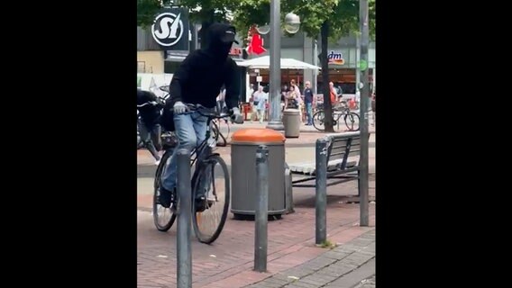 Ein Mann mit einer Maske fährt auf einem Fahrrad nach einem Raubüberfall davon. © HannoverReporter 