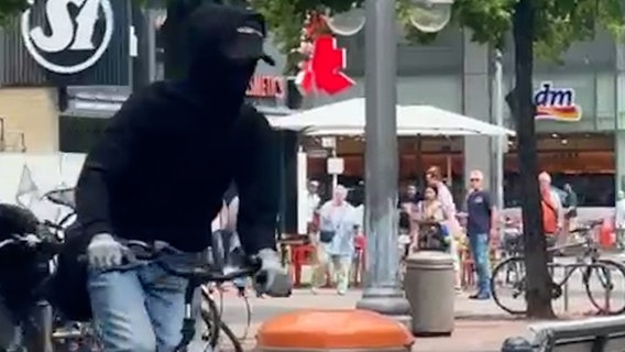 Ein Mann mit einer Maske fährt auf einem Fahrrad nach einem Raubüberfall davon. © HannoverReporter 