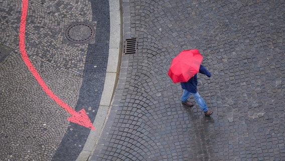 Ein Mann läuft mit einem Regenschirm über eine Straße in Hannover. © picture alliance/dpa | Julian Stratenschulte Foto: Julian Stratenschulte