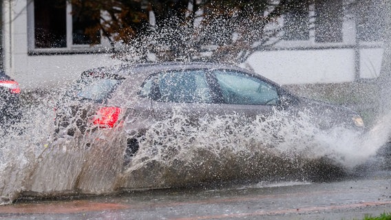 Ein Auto fährt bei Starkregen über eine überflutete Straße in Hannover. © dpa-Bildfunk Foto: Julian Stratenschulte
