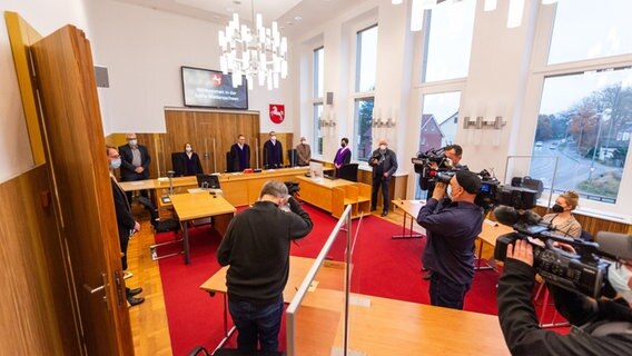 Der Kläger sitzt vor Prozessbeginn im Saal vom Landessozialgericht Niedersachsen-Bremen und hält sich einen Rucksack vor sein Gesicht. © picture alliance/dpa Foto: Philipp Schulze