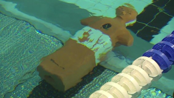 Ein Dummy liegt auf dem Boden eines Schwimmbeckens. © NDR 