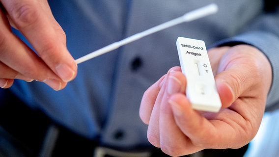 Ein Mann hält einen Schnelltest zur Erkennung des Coronavirus und ein Teststäbchen in einem Pflegeheim in der Region Hannover in den Händen. © dpa-Bildfunk Foto: Hauke-Christian Dittrich