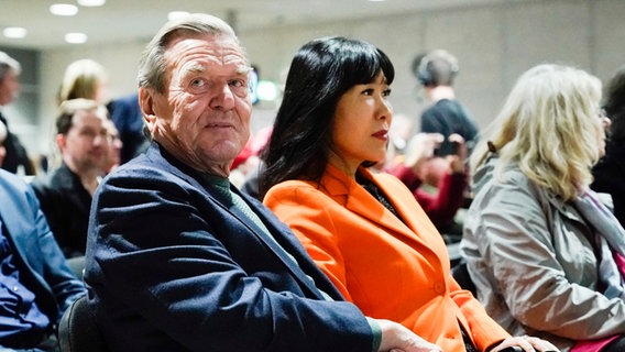 Der ehemalige Bundeskanzler Gerhard Schröder und seine Frau So-yeon Schröder-Kim sitzen in einem Publikum. © picture alliance/dpa | Uwe Anspach Foto: Uwe Anspach