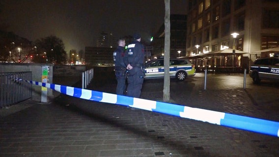 Zwei Polizisten stehen in der Nacht hinter einem Absperrband in einer Straße . © picture alliance/dpa 