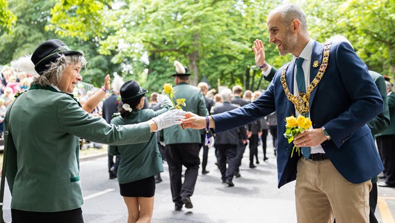 Belit Onay (Bündnis 90/Die Grünen, r), Oberbürgermeister von Hannover, übergibt einer Teilnehmerin vom Schützenausmarsch eine Blume. © dpa-Bildfunk Foto: Michael Matthey