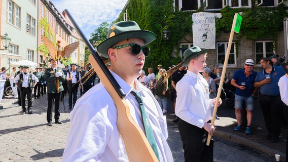Schützen vom Löninger Schützenverein von 1597 e.V. laufen mit Holzgewehren beim Schützenausmarsch durch die Innenstadt. © dpa Foto: Julian Stratenschulte