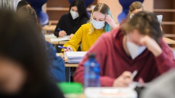 Mädchen und Schüler eines Abiturjahrgangs sitzen mit Masken in einem Klassenraum.  © picture alliance/dpa Foto: Julian Stratenschulte