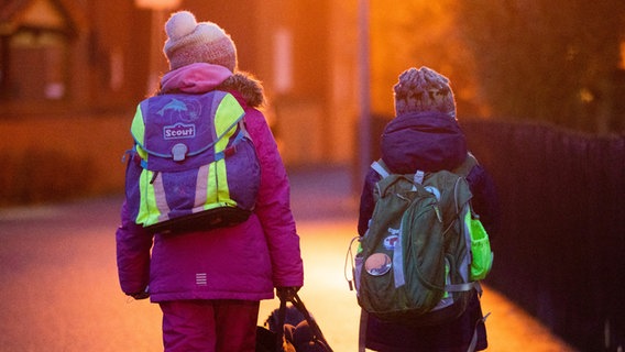 Zwei Schüler*innen gehen am frühen Morgen auf dem Schulweg zu ihrer Grundschule. © dpa-Bildfunk Foto: Julian Stratenschulte
