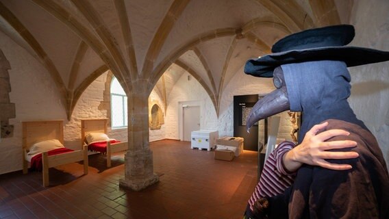 Eine Mitarbeiterin verrückt eine Figur eines Pestdoktors mit einer Schnabelmaske im Roemer- und Pelizaeus-Museum Hildesheim in der Sonderausstellung "Seuchen. Fluch der Vergangenheit - Bedrohung der Zukunft". Eine Mitarbeiterin verrückt eine Figur eines Pestdoktors mit einer Schnabelmaske im Roemer- und Pelizaeus-Museum Hildesheim in der Sonderausstellung "Seuchen. Fluch der Vergangenheit - Bedrohung der Zukunft". © picture alliance Foto: Julian Stratenschulte