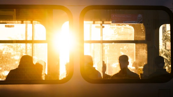 Die Sonne ist durch die Scheiben einer Stadtbahn in Laatzen zu sehen. Fahrgäste zeichnen sich als Umrisse ab. © Julian Stratenschulte/dpa Foto: Julian Stratenschulte/dpa