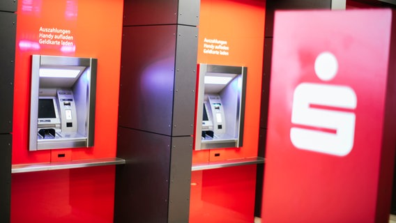 Geldautomaten der Sparkasse Hannover im Vordergrund das weiße Logo der Sparkasse auf rotem Grund. © NDR Foto: Julius Matuschik