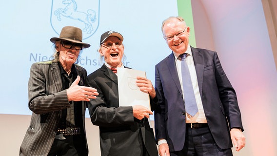 Musiker Udo Lindenberg (l) und Stephan Weil (r, SPD), Ministerpräsident von Niedersachsen, applaudieren Komiker Otto Waalkes (M) nach der Preisübergabe auf der Bühne im Hannover Congress Centrum. © Michael Matthey/dpa Foto: Michael Matthey