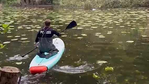 Ein Polizist paddelt mit seinem Stand-up-Paddle-Board auf einem Teich im Landkreis Hildesheim. © Polizei Hildesheim 