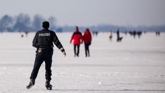 Ein Polizist auf Schlittschuhen kontrolliert die Eisfläche des zugefrorenen Steinhuder Meeres. © dpa-Bildfunk Foto: Moritz Frankenberg