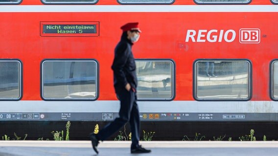 Ein Mitarbeiter der Deutschen Bahn (DB) läuft auf einem Bahnsteig und ein Zug der DB Regio steht auf einem Gleis dahinter. © dpa-Bildfunk Foto: Michael Matthey/dpa