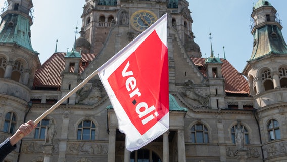 Eine Fahne mit der Aufschrift "ver.di" weht vor dem Neuen Rathaus während einer Kundgebung der Gewerkschaft Verdi auf dem Trammplatz in Hannover. © picture alliance/dpa | Mia Bucher Foto: Mia Bucher