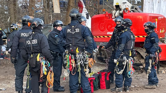 Polizisten mit Kletterausrüstung stehen vor dem Protestcamp in der Leinemasch. © NDR Foto: Niels Kristoph