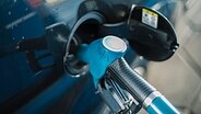 Zapfpistolen an einer Tankstelle in einem Auto. © NDR Foto: Julius Matuschik