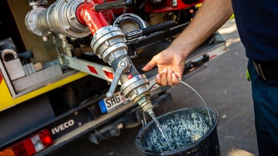 Ein Feuerwehrmann zapft Löschwasser aus einem Tank. © dpa-Bildfunk Foto: Moritz Frankenberg