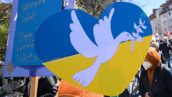 Eine Demonstrantin mit einem Herz in Farben der Ukraine mit einer aufgemalten Friedenstaube läuft beim Ostermarsch 2022. © picture alliance/dpa/Julian Stratenschulte Foto: Julian Stratenschulte