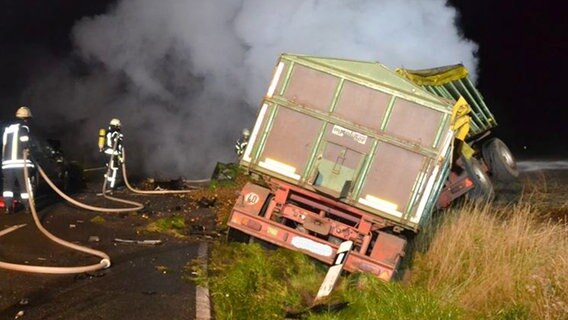 Feuerwehrleute löschen einen brennenden Traktor nach einem Unfall. © Polizeiinspektion Celle 