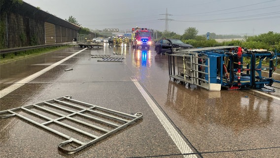 Części przyczepy i przewrócona platforma do robót wysokościowych leżą na drodze po wypadku na autostradzie A7, w tle widać pojazdy uprzywilejowane.  © Lehrte Ochotnicza Straż Pożarna 