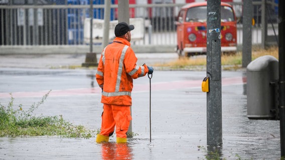 Ein Mitarbeiter der Stadtentwässerung der Stadt Hannover steht auf der überfluteten Hermesallee am Messegelände. © picture alliance/dpa | Julian Stratenschulte Foto: Julian Stratenschulte
