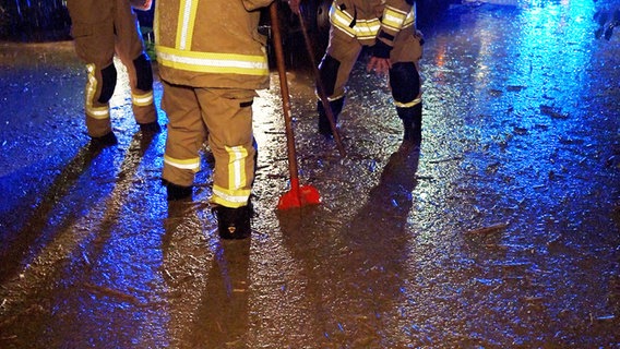 Feuerwehrmänner stehen in Bad Münder (Landkreis Hameln-Pyrmont) nach einem Unwetter mit Starkregen im Schlamm. © HR 