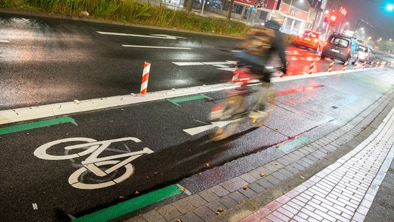 Ein PKW fährt neben einem Fahrrad-Schutzstreifen in Hamburg –   - Mobilität in Szene gesetzt