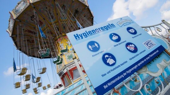 Eine Tafel mit Hygieneregeln ist vor einem Fahrgeschäft am Schützenplatz in Hannover zu sehen. © dpa-Bildfunk Foto: Julian Stratenschulte