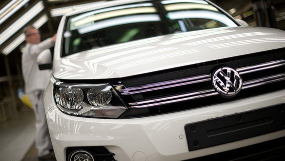 Ein Volkswagen-Mitarbeiter kontrolliert im VW-Werk in Wolfsburg im Lichttunnel für die Endabnahme ein Fahrzeug vom Typ Tiguan. © dpa-Bildfunk Foto: Jochen Lübke