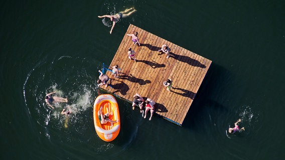 Ein Steg und schwimmende Menschen von oben im Wasser sind zu sehen. © dpa-Bildfunk 