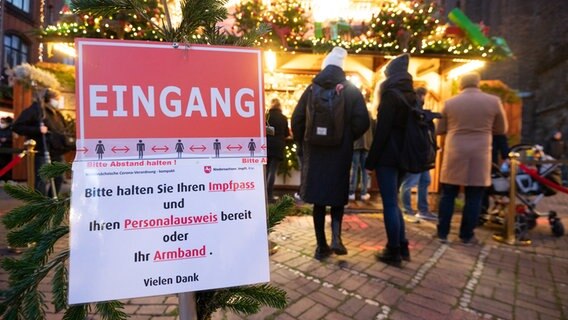 An information sign "Please have your vaccination certificate and ID card ready or your wristband" stands at a mulled wine stand at a Christmas market in Hanover.  © dpa Photo: Julian Stratenschulte