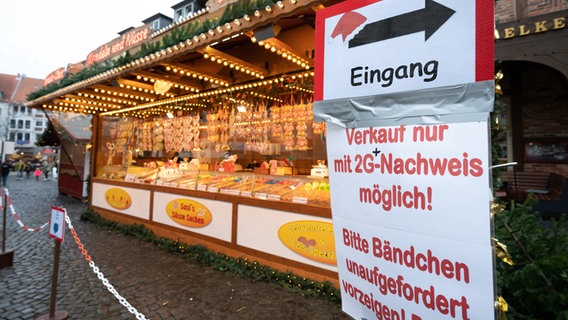 Ein Schild auf dem Hildesheimer Weihnachtsmarkt weist auf die 2G-Plus-Regel hin. © picture alliance Foto: picture alliance/dpa | Julian Stratenschulte
