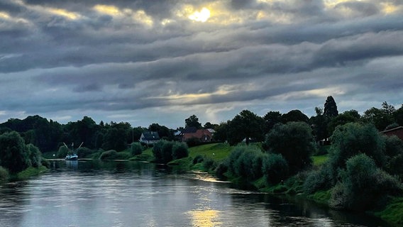 Sonne scheint scheint durch einen grauen Wolkenhimmel auf einen Seitenarm der Weser. © NDR Foto: Tanja Scheer