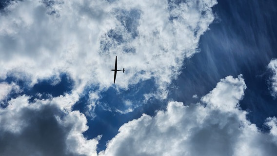 Blick von unten auf ein Flugzeug an blauem Himmel mit Wolken. © NDR Foto: Dirk Wenzel