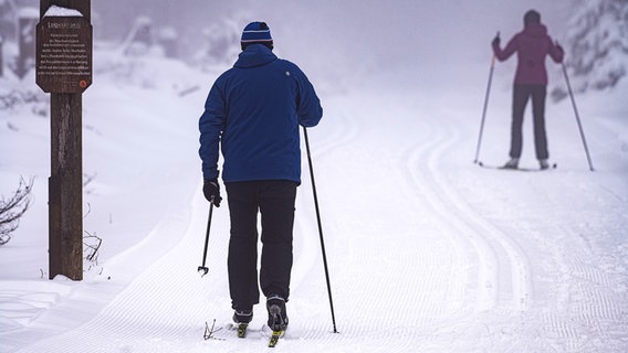Wintersportler sind mit ihren Skiern auf einer Langlaufstrecke am Sonnenberg im Harz unterwegs. © dpa-Bildfunk Foto: Swen Pförtner