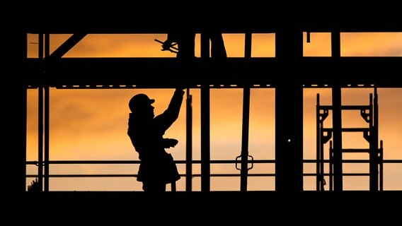 Bauarbeiter bauen bei Sonnenaufgang an einem Wohnhaus. © picture alliance/Julian Stratenschulte/dpa Foto: Julian Statenschulte