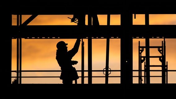 Bauarbeiter bauen bei Sonnenaufgang an einem Wohnhaus. © picture alliance/Julian Stratenschulte/dpa Foto: Julian Statenschulte