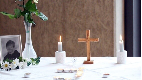 Kerzen, ein Kruzifix und ein Foto des gestorbenem Schülers stehen im Andachtsraum der IGS Wunstorf. In Wunstorf ist ein 14-Jähriger mutmaßlich getötet worden. © Lothar Veit/Landeskirche Hannover Foto: Lothar Veit