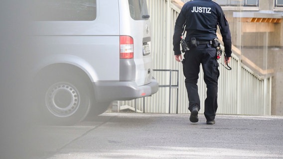 Ein Justizbeamter läuft vor dem Landgericht Hannover neben einem Gefangenentransporter der Jugendanstalt Hameln. © dpa-Bildfunk Foto: Julian Stratenschulte