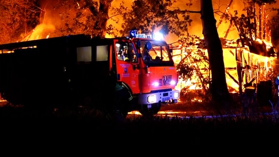 Ein Feuerwehrauto vor einem brennenden Gebäude (Großbrand einer Scheune). © NonstopNews 