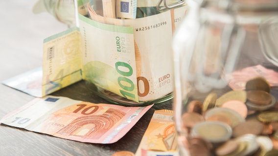 Diverse Euromünzen und Geldscheine in Einmachgläsern und auf einem Tisch. © picture alliance/dpa-tmn Foto: Christin Klose